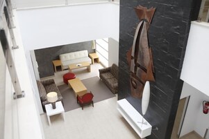 Una sala moderna con sofá, mesa de centro y una silla roja. Se observa una chimenea a la derecha.