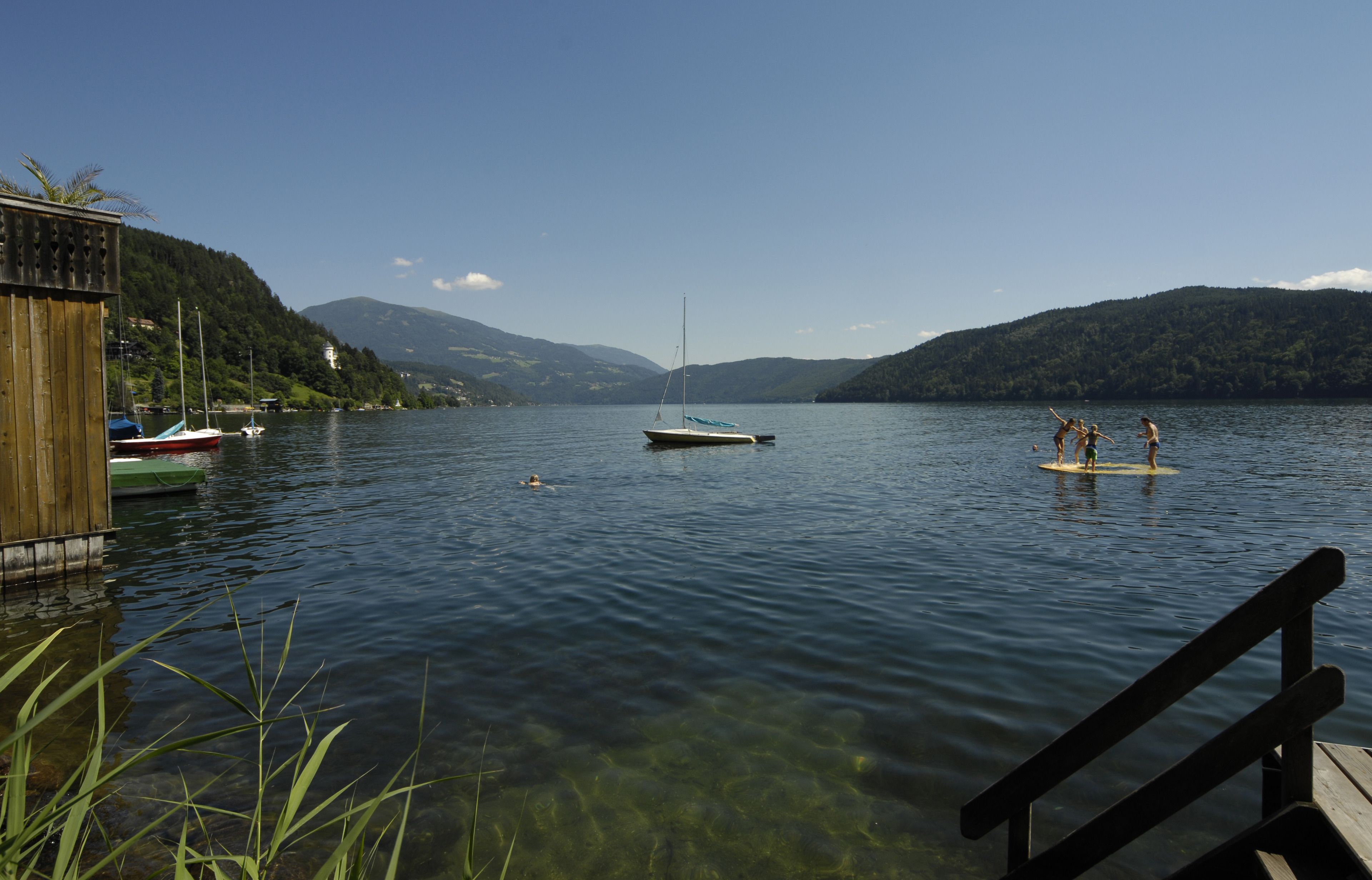A calm lake with boats, a dock, and a wooden pier.
