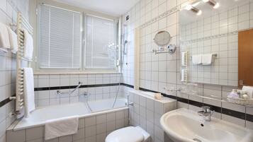 Un baño con bañera, inodoro, lavabo y una ventana con persianas.