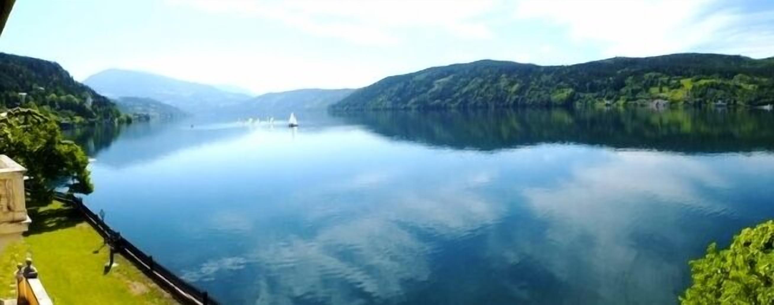 A serene lake with a boat, surrounded by lush greenery and hills.