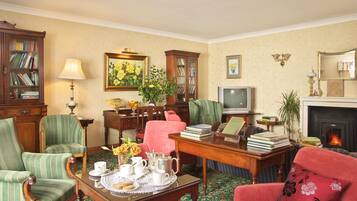 A traditional living room with a fireplace, a television, and a bookshelf.