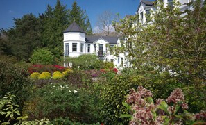 A large white building with a turret, surrounded by lush gardens and trees. - Seaview House Hotel (Bantry)