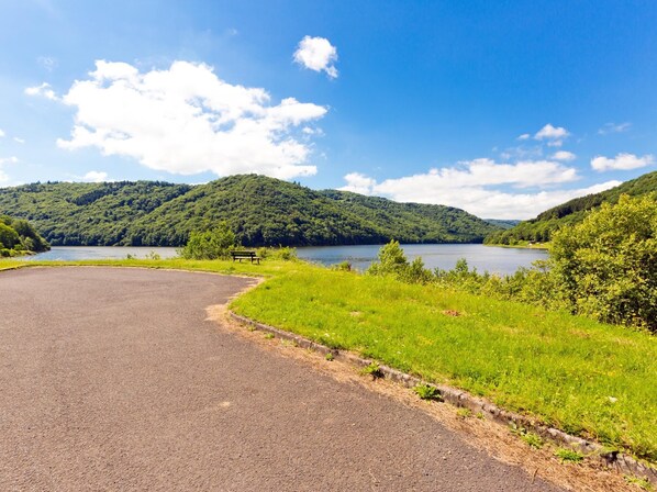 A paved area with a bench and a lake surrounded by hills.