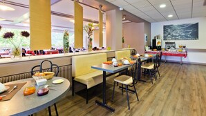 A modern dining area with round tables, benches, and chairs. There are decorative plants and a coffee machine on the tables. - Hôtel Restaurant Belle Vue (Les Ancizes-Comps)