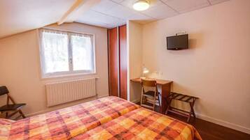 A bedroom with two beds, a desk, a chair, a radiator, and a TV on the wall.