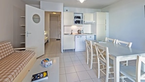 A compact living space with a kitchenette, a dining area, and a bedroom. - Vacancéole Le Domaine de Bertheaume (Plougonvelin)