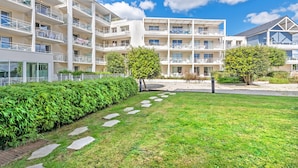 A multi-story hotel with balconies, a grassy courtyard, and a clear blue sky. - Vacancéole Le Domaine de Bertheaume (Plougonvelin)