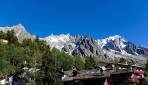 A mountain landscape with snow-capped peaks and a village with traditional houses.