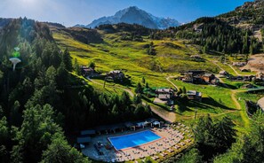 Eine gebirgige Landschaft mit einem Schwimmbecken und umliegenden Gebäuden.