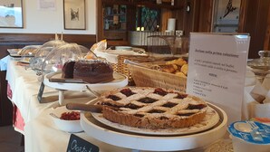 Een buffet met diverse desserts, waaronder een taart en een cake, en een bord met de menukaart.