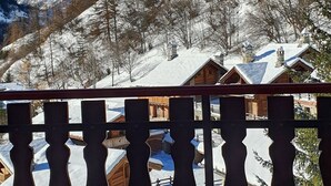 Bergzicht met besneeuwde toppen en een houten chalet op de voorgrond.