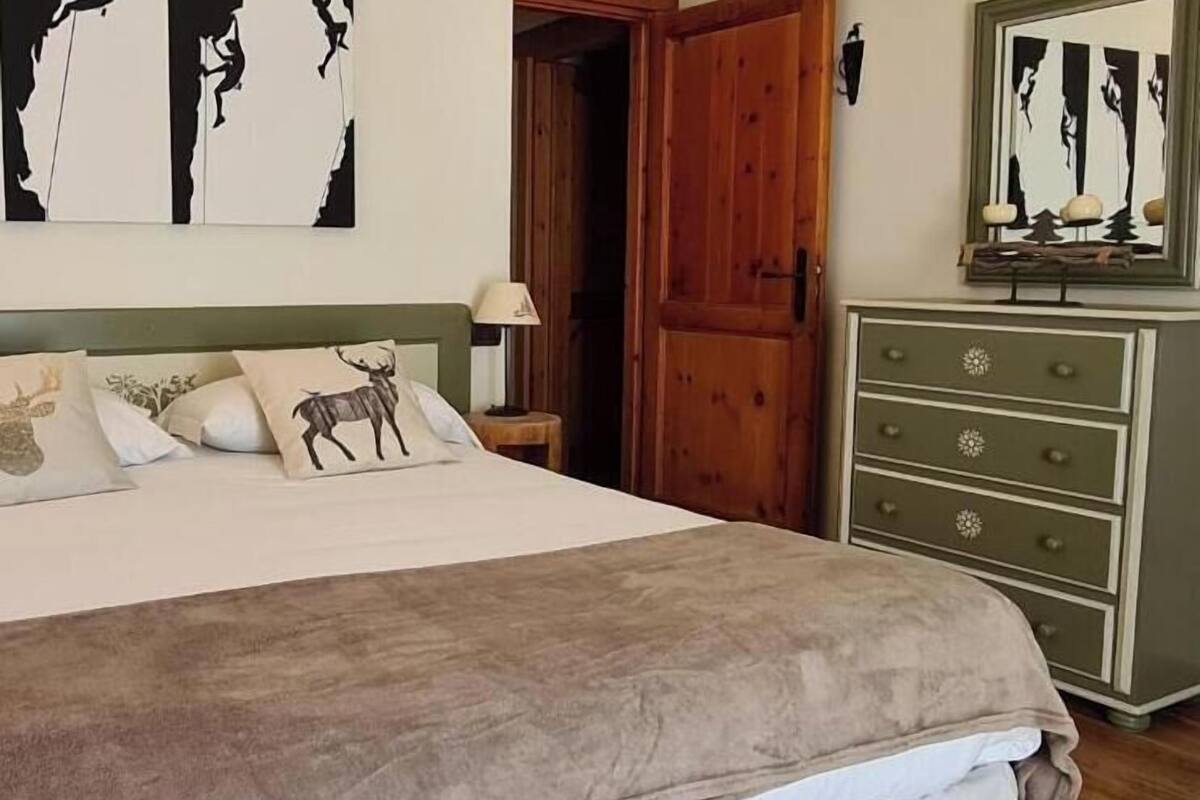 Une chambre à coucher avec un lit, une commode, une porte et des œuvres d’art murales.