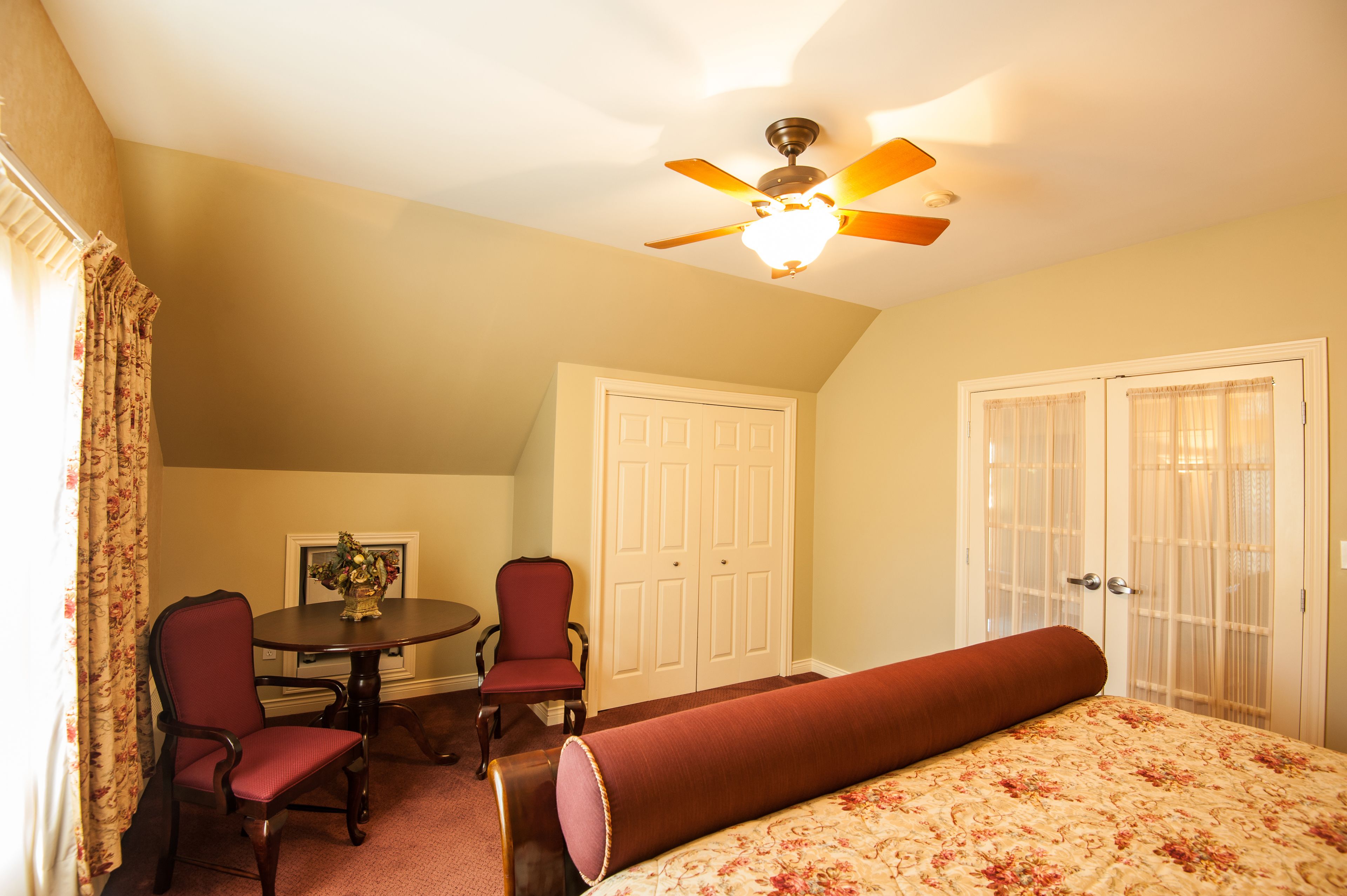 Une chambre à coucher avec un lit, une chaise, une table et un ventilateur de plafond.