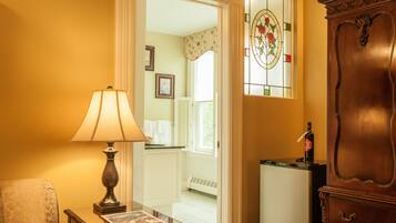A room with a lamp, a wooden cabinet, and a door leading to another room.