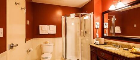 A bathroom with a glass-enclosed shower, a toilet, a sink with a vanity, and a large mirror.