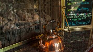 A copper teapot on a granite countertop with a metal mesh screen in the background.