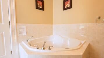 A bathroom with a large bathtub, two framed pictures on the wall, and a towel ring.