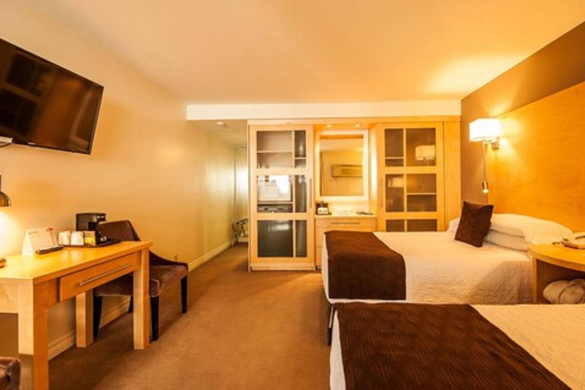 Ein Hotelzimmer mit Bett, Schreibtisch, Stuhl, Fernseher und Kleiderschrank.