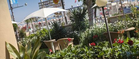 An outdoor seating area with white umbrellas, chairs, and potted plants.