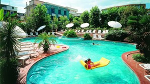 A swimming pool with a yellow inflatable raft, surrounded by lounge chairs and umbrellas, with buildings in the background. - Hotel San Giorgio Savoia (Bellaria-Igea Marina)