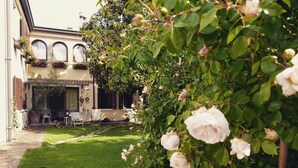 Un cortile con giardino, posti a sedere all'aperto e un edificio con finestre ad arco.