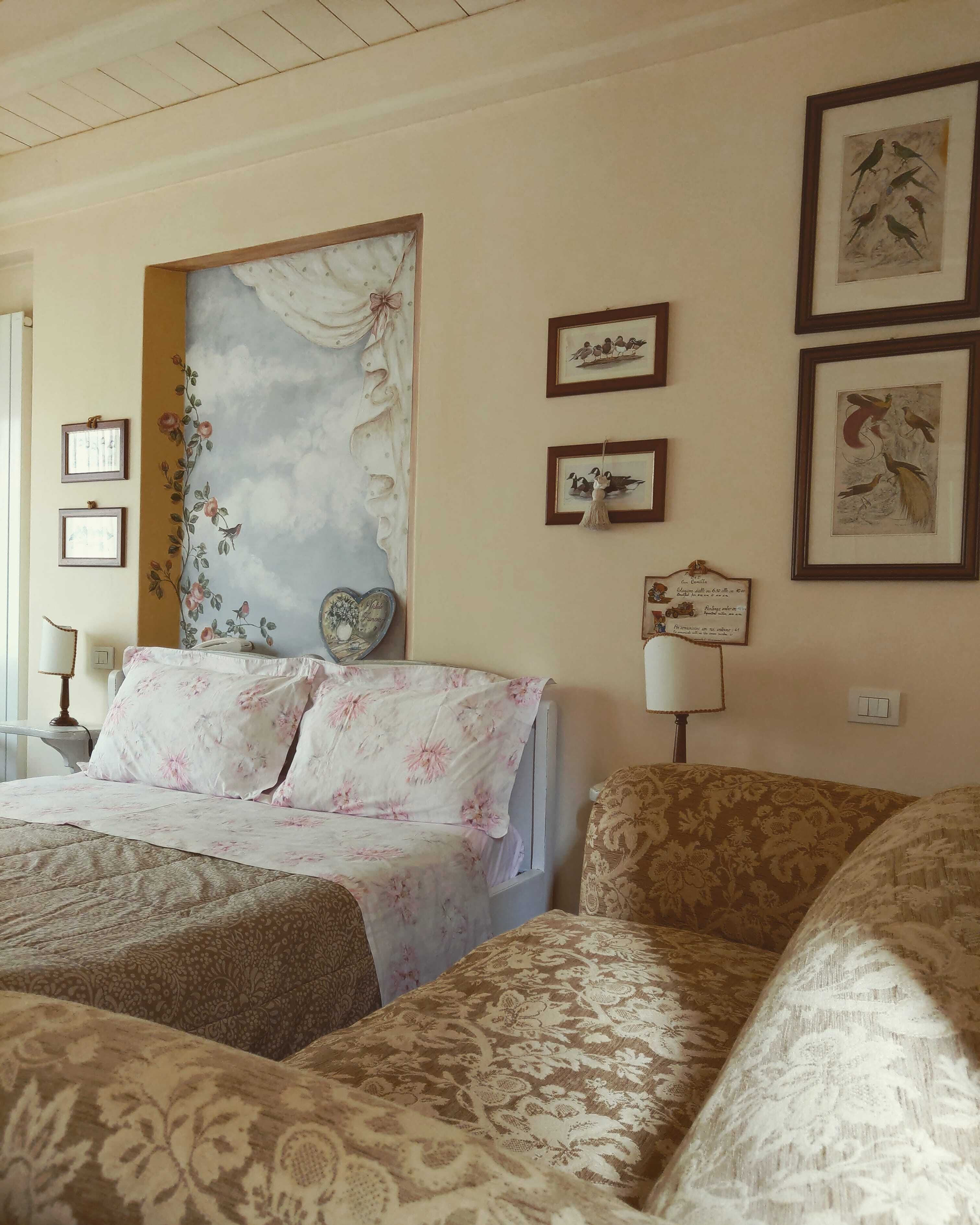 Une chambre d’hôtel avec un grand lit, un petit canapé et un mur décoratif orné de tableaux encadrés.