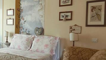 Une chambre d’hôtel avec un grand lit, un petit canapé et un mur décoratif orné de tableaux encadrés.