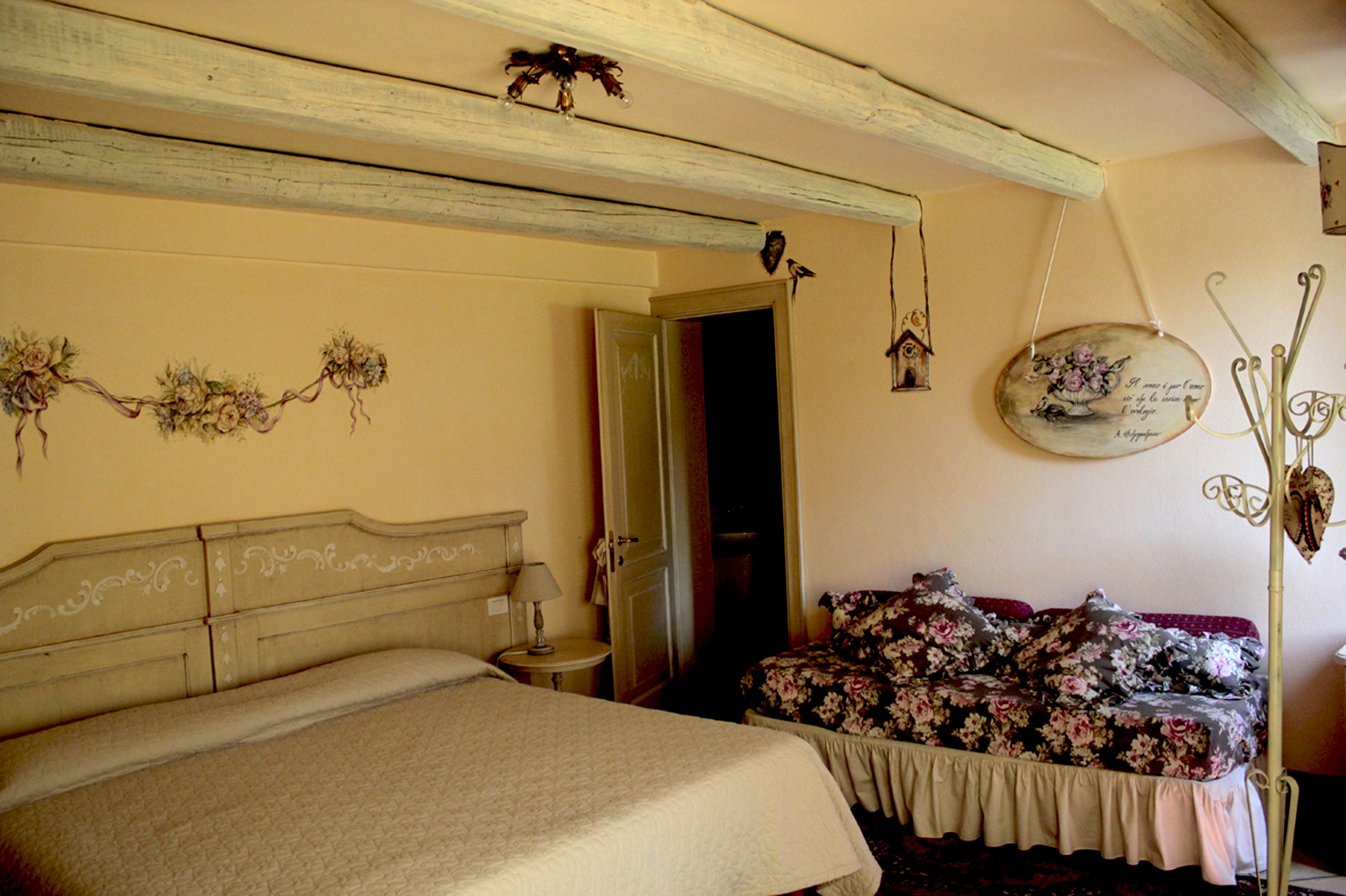 A bedroom with a bed, a nightstand, a dresser, and a floral sofa.