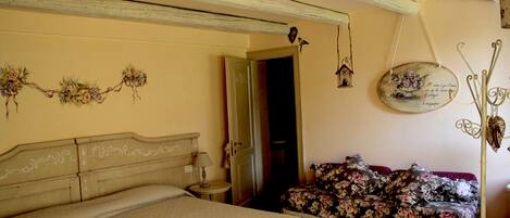 A bedroom with a bed, a nightstand, a dresser, and a floral sofa.