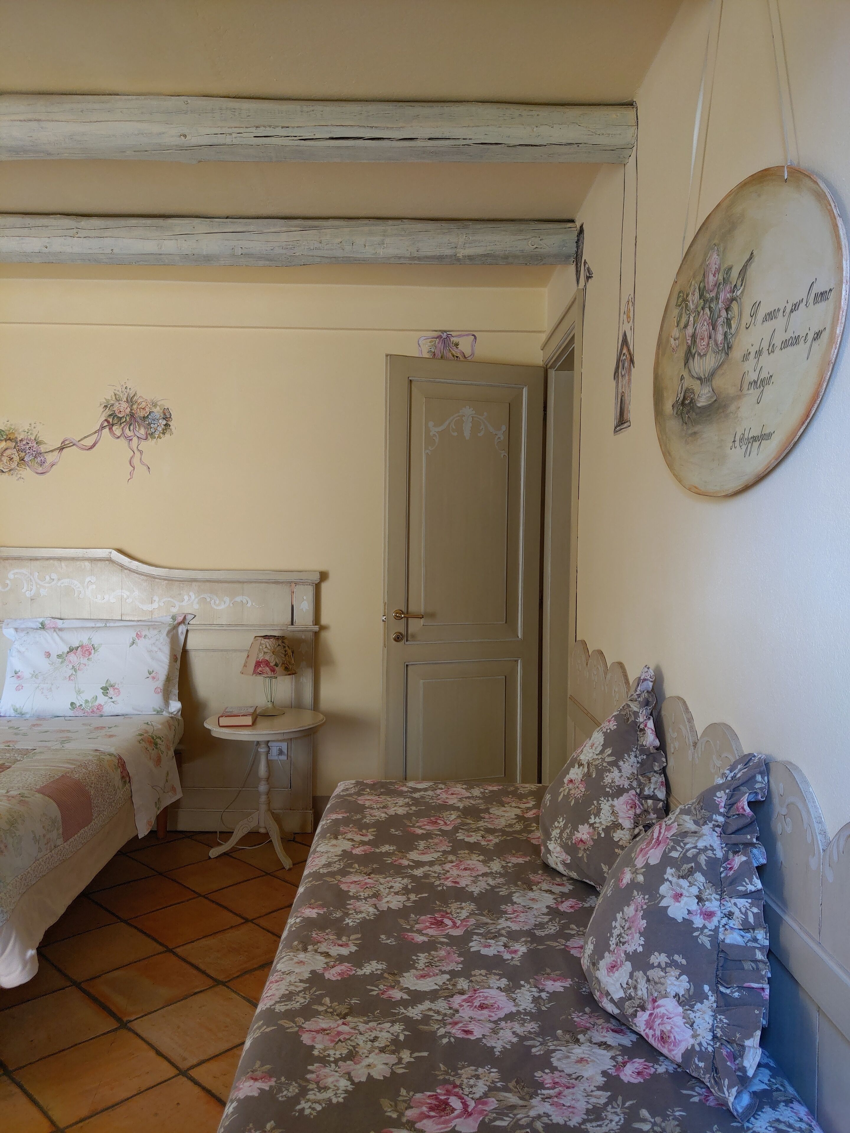 Ein Schlafzimmer mit zwei Betten, einem kleinen Nachttisch, einer Tür und einer Wanddekoration.