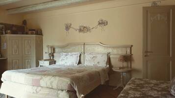A bedroom with a large bed, a smaller bed, a nightstand, a lamp, and a wardrobe.