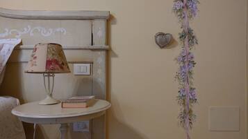 A room with a round table, a lamp, a book, a light switch, a power outlet, and a decorative floral garland.