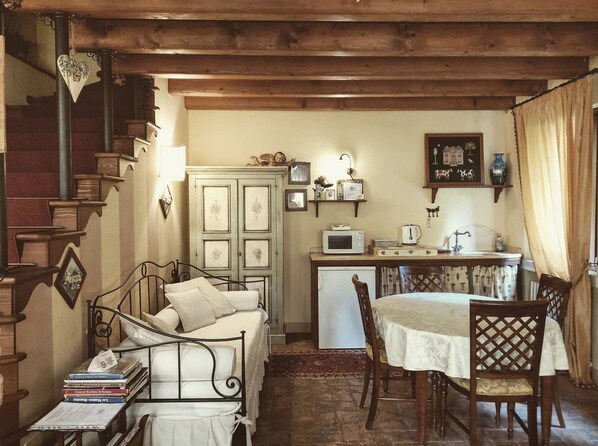Une pièce confortable comprenant un lit, un bureau avec un ordinateur, un petit réfrigérateur et une table à manger avec des chaises.