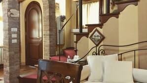 Una stanza accogliente con soffitto in legno, un letto con lenzuola bianche, una sedia rossa e una parete in mattoni.