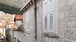 Una calle estrecha con edificios de piedra, contraventanas blancas y tejados de teja.
