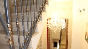 Una escalera con barandillas de metal ornamentadas y un candelabro.