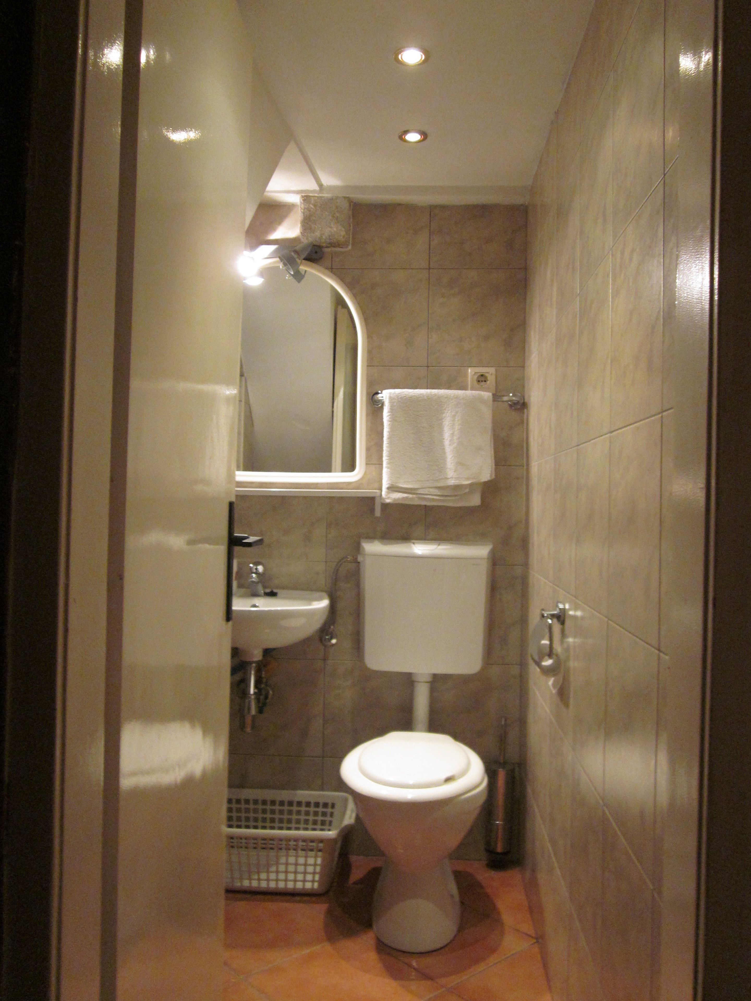 A compact bathroom with a toilet, sink, and mirror.