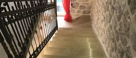A staircase with a stone wall on one side and a black metal railing on the other.