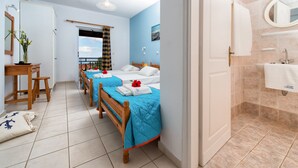Ein Hotelzimmer mit zwei Betten, einem Holztisch, einem Stuhl, einem Badezimmer inklusive Waschbecken und Spiegel sowie einem Balkon mit Blick.