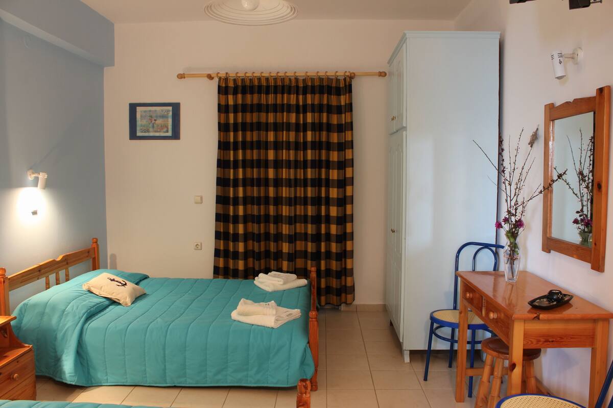 Un dormitorio con cama, escritorio, silla, armario y cortina.
