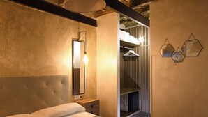 Un dormitorio con cabecera capitonada, una mesita de noche, una lámpara colgante y un espejo.