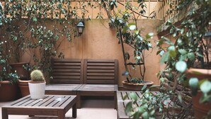 An outdoor patio with wooden benches and potted plants. - Dulcis Inn Pantheon (Rome)