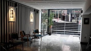 Um lobby moderno com paredes listradas, piso lustroso e área de estar com cadeiras e uma mesa.