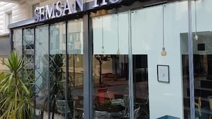 Um hotel com fachada moderna, amplas janelas de vidro e uma placa com a inscrição "SEMSAN HOTEL".