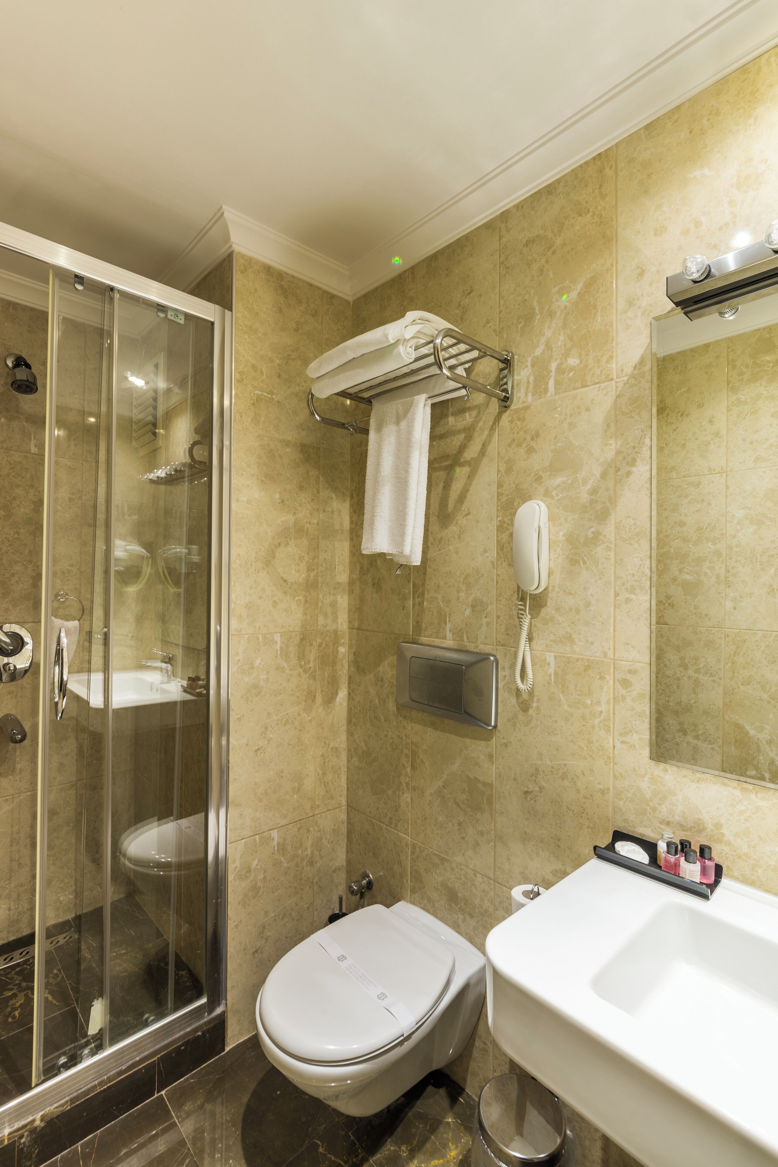 Un baño con ducha de mampara de vidrio, inodoro, lavamanos y espejo.
