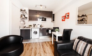 A compact kitchen with modern appliances, a dining area with a table and chairs, and a living area with a sofa and a coffee table. - Parnell Square Apartments (Dublin)