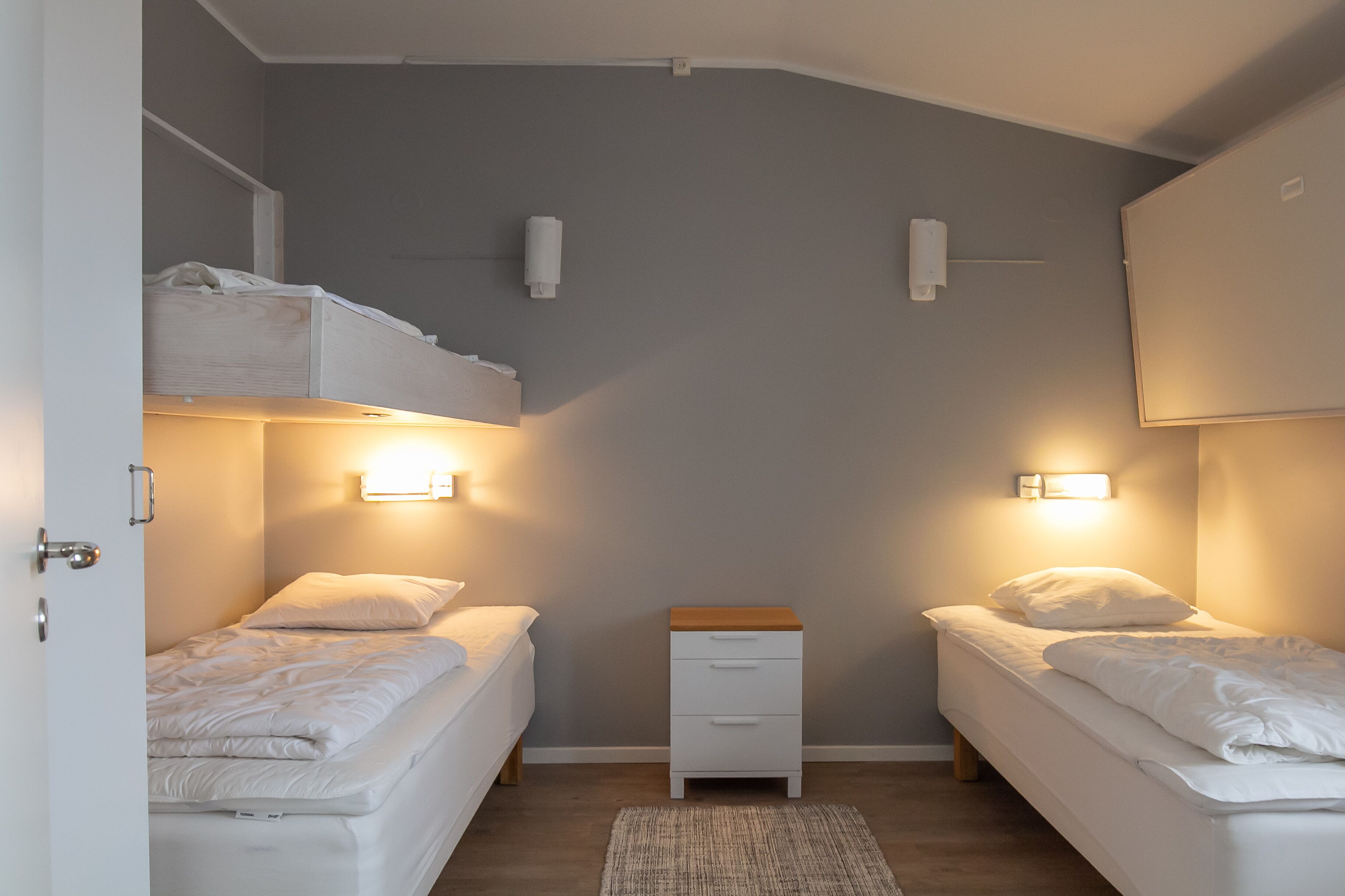 Een slaapkamer met twee enkele bedden, een nachtkastje en wandlampen.