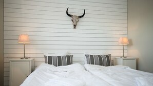 Ein Hotelzimmer mit einem Bett, zwei Nachttischen, Lampen und einem an der Wand befestigten Stierkopf.