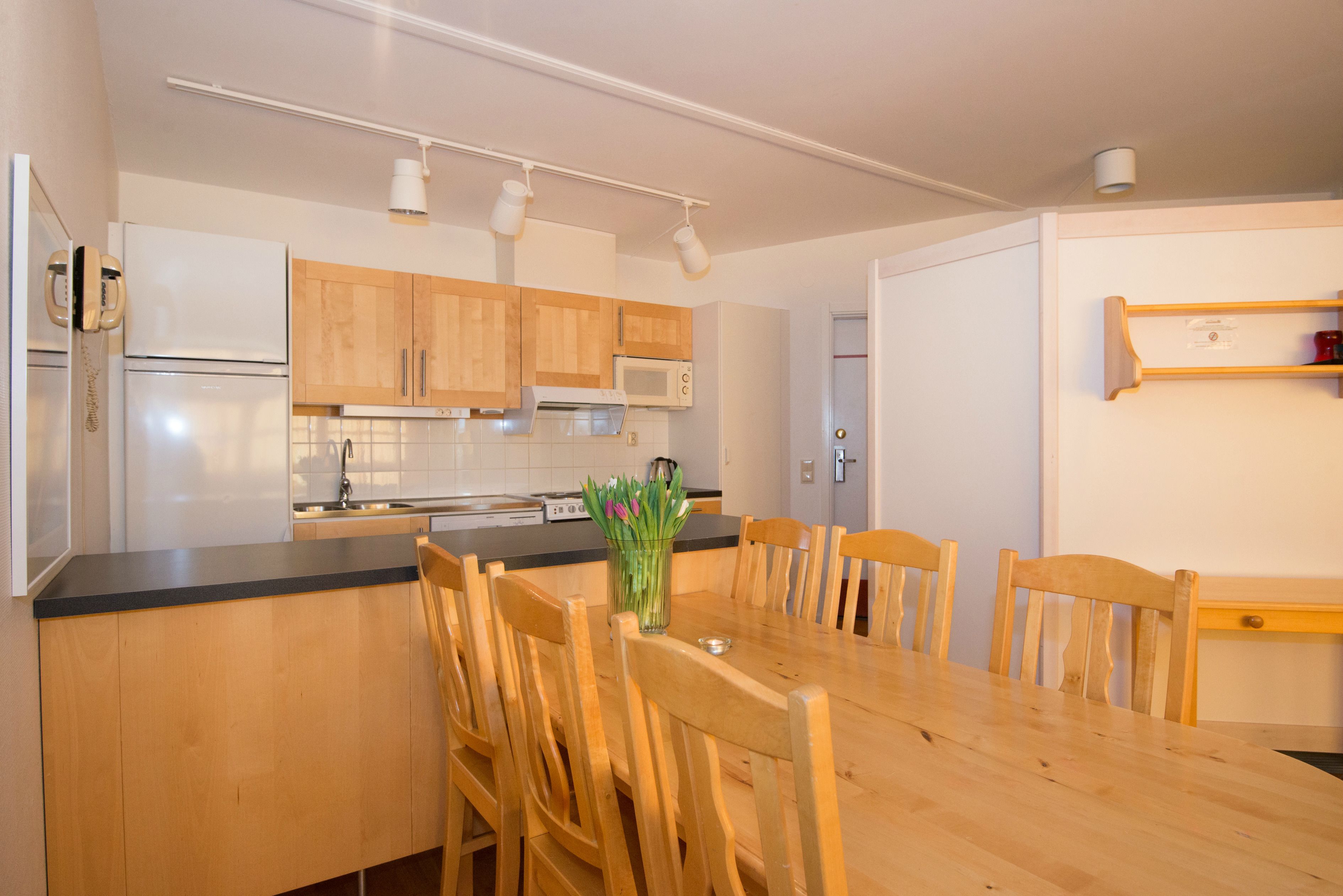 Une cuisine moderne avec des meubles de rangement en bois, un plan de travail noir et une table à manger avec des chaises.