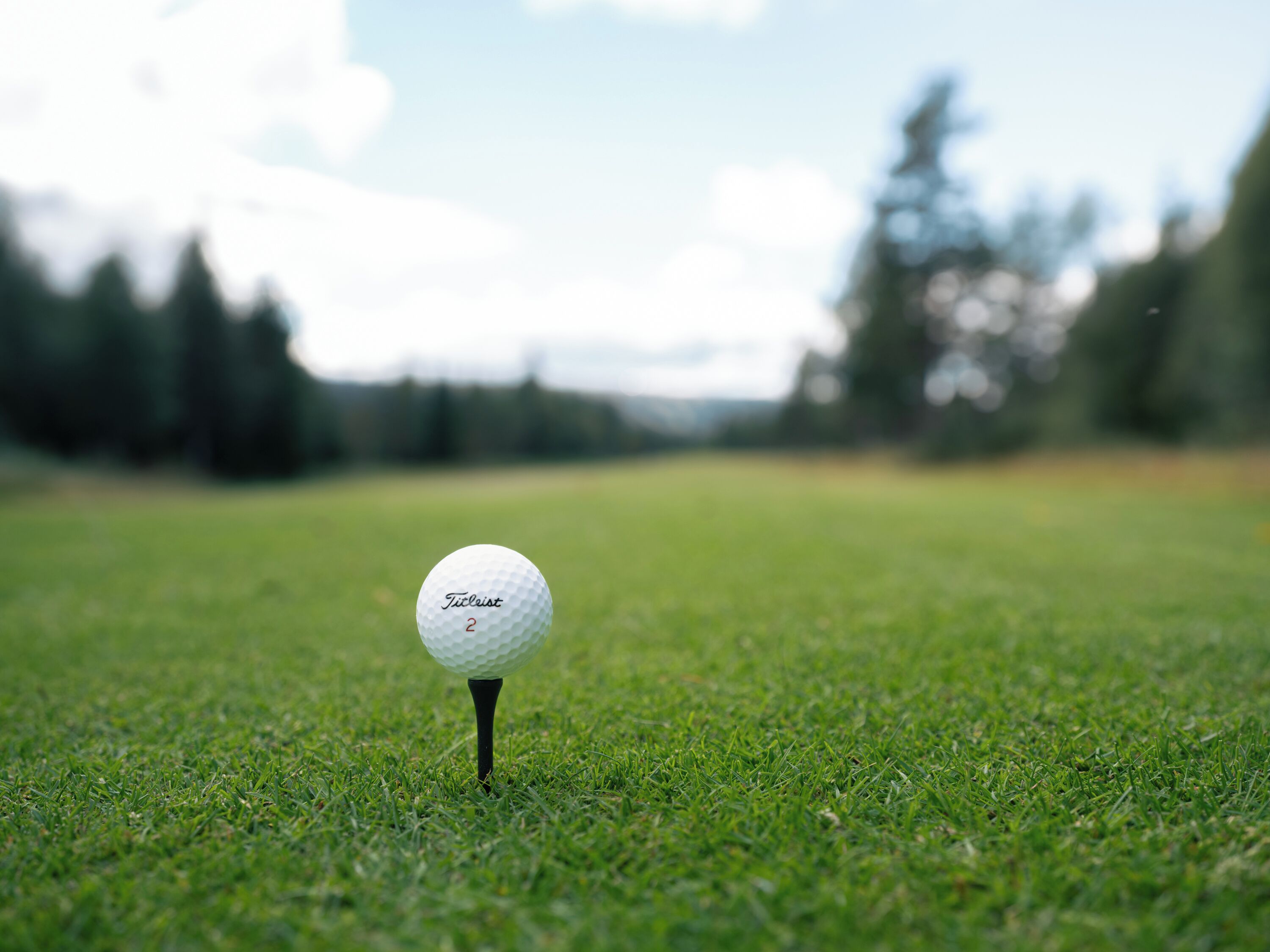 Une balle de golf posée sur un support, sur un terrain herbeux.